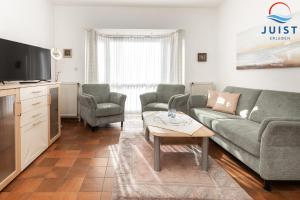 a living room with a couch and chairs and a tv at Haus Insa 145 - Ferienwohnung elf in Juist