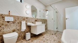 a bathroom with a toilet and a sink and a mirror at Cornerstone Manor Kathu in Kathu +59 photos