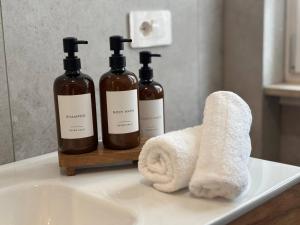 three bottles of soap and a towel on a bathroom sink at Casa Angelina in Barlassina +48 photos
