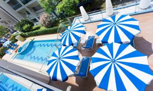 un grupo de sombrillas azules y blancas junto a una piscina en Princess Aparthotel en Bibione