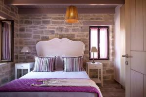 1 dormitorio con 1 cama con 2 mesas y pared de piedra en Phaistos Villas - Private Pool Luxury Retreats, en Sívas