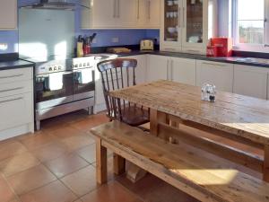 a kitchen with a wooden table and a wooden bench at Granary Cottage in Bentley