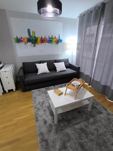 ein Wohnzimmer mit einer schwarzen Couch und einem Couchtisch in der Unterkunft El Piso de Montse in A Coruña + 36 Fotos