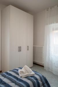 a bedroom with white cabinets and towels on a bed at lachiocciola - Centro storico di Imola, autodromo e Formula 1 in Imola