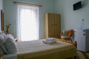 Schlafzimmer mit einem Bett, einem Kühlschrank und einem Fenster in der Unterkunft Panorama Rooms in Pyrgos Dirou