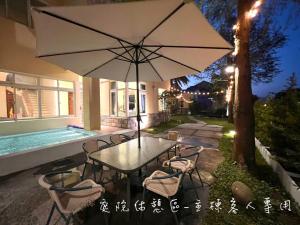 a table and chairs with an umbrella in front of a house at Annongriver B&B in Sanxing