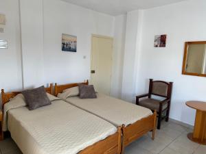 a bedroom with two beds and a chair at Terpsithea Apartments in Ayia Napa