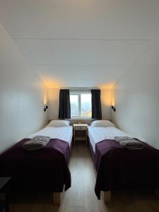 two beds in a room with a window at The Vík Inn by Ourhotels in Vík
