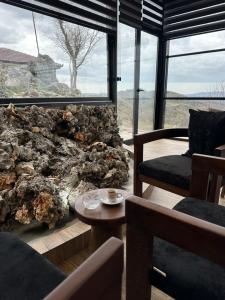 a living room with a large window and a stone fireplace at Bujtina Sakollari in Poliçan