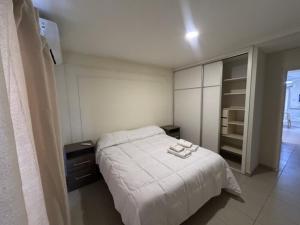 Un dormitorio con una cama blanca con dos toallas encima. en HOUSE AND SUITE SF RIVADAVIA, en Santa Fe