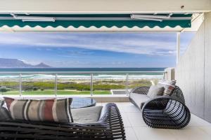 a balcony with wicker chairs and a view of the ocean at Dolphin Beach Penthouse in Cape Town