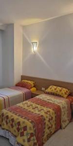 a bedroom with two beds and a light on the wall at La douceur de Hammamet in Yasmine