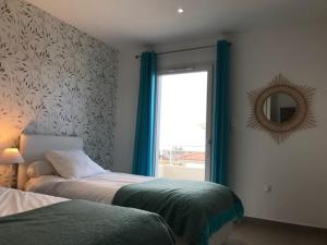 1 Schlafzimmer mit 2 Betten und einem Fenster mit einem Spiegel in der Unterkunft PDM Appartement Paese di Mare in Santa-Lucia-di-Moriani