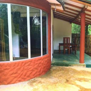 a porch of a house with a table and a chair at Dramatic Green Cottage in Udawalawe