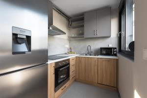 a kitchen with stainless steel appliances and wooden cabinets at Theeta Villas by RentalsPro - Metamorfosi Halkidiki in Metamorfosi