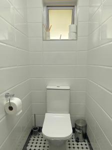a white bathroom with a toilet and a window at Sleep on 489 in Pretoria