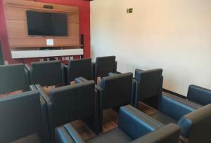 a waiting room with chairs and a flat screen tv at Golden Lake Residence Apart Hotel in Arraial do Cabo +278 photos