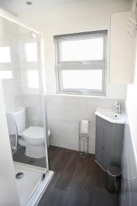 a bathroom with a toilet and a sink and a window at Stylish 3Bed House with Garden, near Stations, London & Harry Potter studios, great for families and contractors in Watford West Station +20 photos