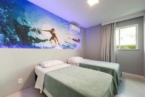 a room with two beds and a painting of a surfer at Golden Lake in Arraial do Cabo +274 photos