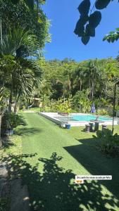 a yard with a swimming pool and palm trees at Flats Ponta do Sapê in Angra dos Reis