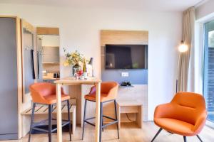a dining room with orange chairs and a table at Ferienwohnung Waldkauz 23 im Wreecher Idyll Rügen by ruyastay in Putbus +3 photos