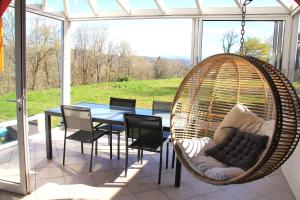 a porch with a table and chairs and a swing at DOMAINE DE LA TISNERE in Gelos