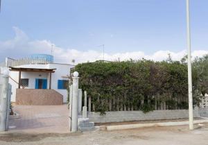a fence in front of a house with a building at Villa Azzurra con piscina e con vista mare fronte Spiaggia Specchiarica di San Pietro in Bevagna in Torre Colimena