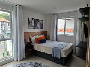 a bedroom with a bed and two large windows at Zu Hause, sua casa em Blumenau in Blumenau +13 photos