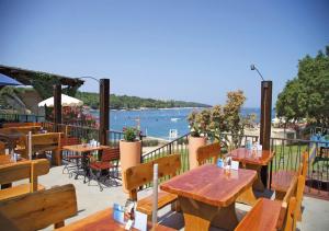 a restaurant with tables and chairs and a view of the water at Camping Lanterna - Eurocamp I Homair in Poreč