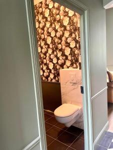 une salle de bain avec toilettes avec des fleurs sur le mur dans l'établissement Petite Maison de Famille de Charme en Vallée du Lot, à Lédat