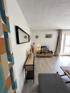 un soggiorno con un tavolo e una TV di LE COLORÉ - Parking gratuit - Confortable a Pau