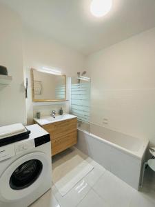 une salle de bain blanche avec une machine à laver à l'intérieur dans l'établissement le Nid des Cèdres, voisin des Thermes et du centre, à Thonon-les-Bains