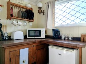 a kitchen with a counter top with a microwave at Galahad - Shepherd's Hut in Northrepps