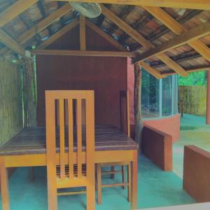 a wooden table and chairs under a wooden roof at Dramatic Green Cottage in Udawalawe