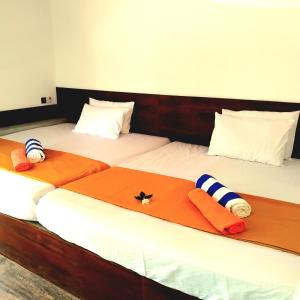 two beds in a room with towels on them at Dramatic Green Cottage in Udawalawe