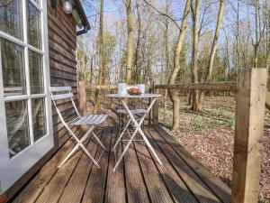 una mesa y sillas en una terraza de madera con árboles en Woodlands Retreat Shepherd's Hut, en Woodbridge 6 fotos más