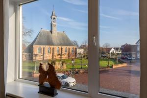 a window with a teddy bear in front of a church at Welcome in - Appartementen Pleinzicht, met zonnige balkon I Dorpsplein 6 Koudekerke in Koudekerke +51 photos