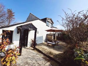 una casa bianca con tavolo da picnic e panca di Hallagenna Cottages a Bodmin