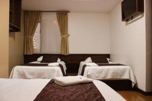a room with three beds and a flat screen tv at HOSTAL CAMIL in Loja +22 photos