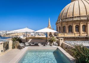 a swimming pool on top of a building with a church at Old Theatre Suites - Tremiti in Valletta