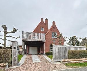 a red brick house with a white fence at Villa Charme - Koksijde in Koksijde