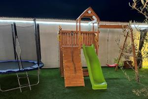 a playground with a green slide and a swing at Guest House Doni in Sandanski