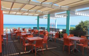una terraza con mesas y sillas y la playa en serra alimini 2, en Otranto