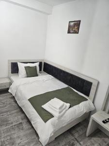 a bedroom with a bed with a green and white blanket at Casa 1 Mai in Curtea de Argeş