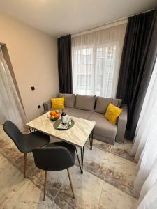 a living room with a table and a couch at GRAND APARTMENT OHRID - top center near to sea and sea garden in Burgas City