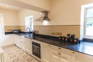 a kitchen with white cabinets and black counter tops at The Chapel Suite in Marske +8 photos