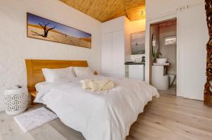 a bedroom with a white bed with a stuffed animal on it at Enso Botanico Boutique Villa, Kosmos in Hartbeespoort