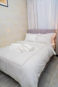 een groot wit bed met witte lakens en kussens bij KML Luxury Kinshasa-Gombe in Kinshasa +28 foto's