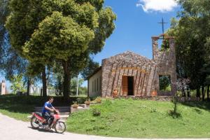 a man riding a motorcycle in front of a church at Flor de Espinillo Estancia Grande in Estancia Grande