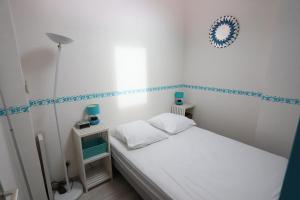 a small bedroom with a white bed and blue trim at Argeles sur Mer jolie maison avec terrasse et piscine in Plage dʼArgelès
